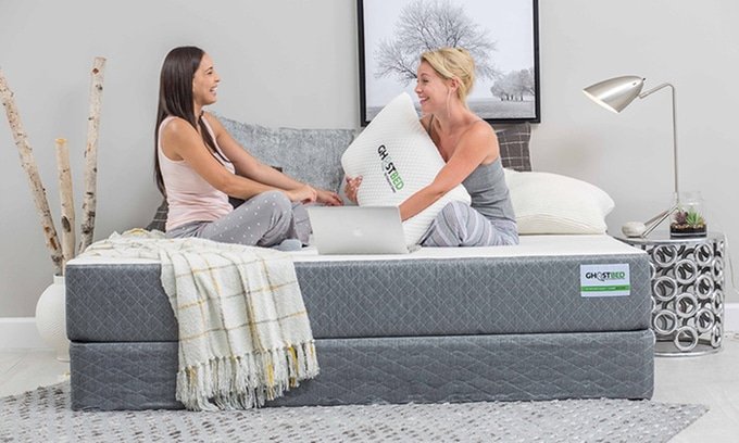 Ghostbed Two ladies sitting on a new Ghostbed mattress and boxspring