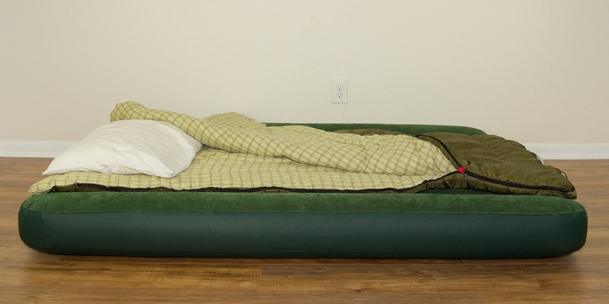 A fully made up air mattress with pillow and bedding