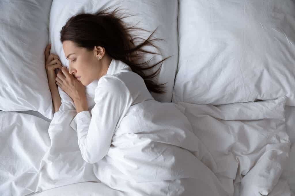Above view upset worried lonely woman lying in bed alone suffers from insomnia